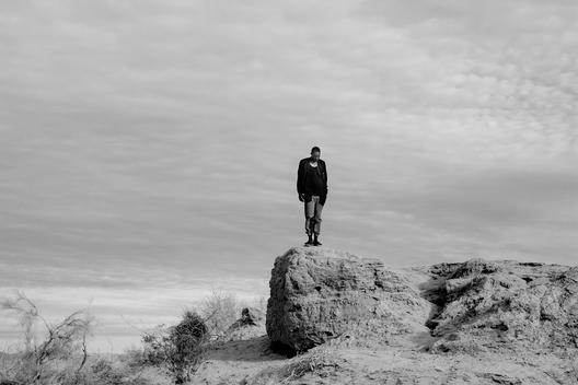 Black male model standing on a rock in the desert.