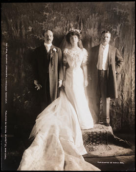 Alice Roosevelt Longworth, Nicholas Longworth And President Theodore Roosevelt Standing In Front Of A Decorative Curtain At The White House In Washington, D.C. She Is Standing In Her Wedding Dress And The Men Are In Tuxedos And Top Coats.