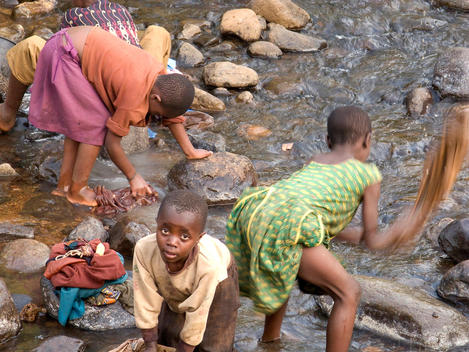 Children washing clothes in the same stream where they take their drinking water