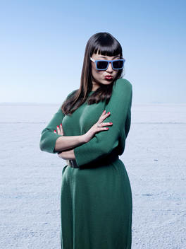 A girl wearing sunglasses stands smiling on bright white salt flats