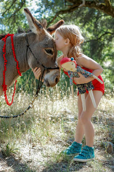 girl with doll kissing donkey