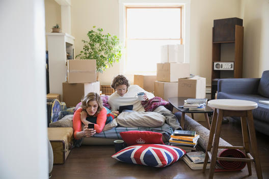 Couple using technology surrounded by moving boxes