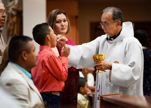 Priest giving communion during mass in Catholic church