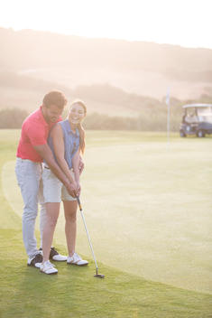 Man teaching woman to golf