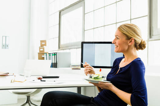 Germany, Businesswoman eating salad, smiling