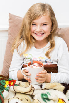 Smiling little girl holding cup of cacao, studio shot