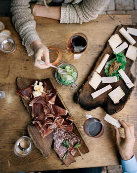 A couple enjoy Savoie charcuterie and cheeses, including Reblochon Fermier, Persill_, and Tomme at a restaurant in the Haute Savoie region of France.