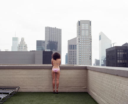 .A Woman In A Bikini Looks Over The Edge Of A New York City Skyscraper.