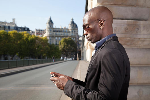 Profile of professional man using mobile phone, European city in background