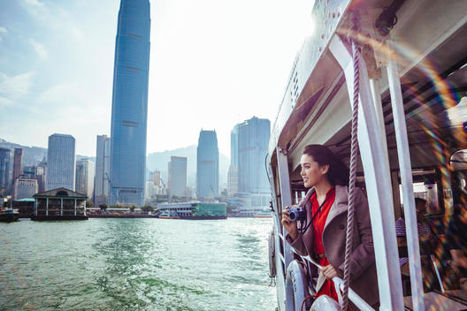 A woman takes pictures as she rides the Star Ferry across Victoria Harbor in Hong Kong, China.