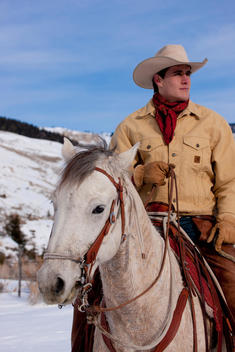 Portrait Of Cowboy Sitting On Horse; Cowboy Looking Away, Horse Looking At Camera.
