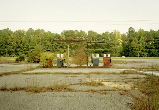 An Abandoned Gas Station With A Police Radar Trap In The Background.