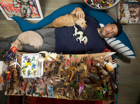 Art dealer, Stefan Simchowitz lies on the floor with his dogs surrounded by art and toy figurines