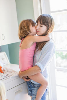 Mother and daughter hugging in utility room, portrait