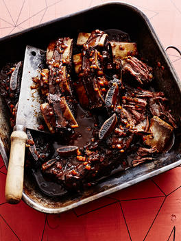 Roasting tin of short ribs braised in black sauce with butchers knife