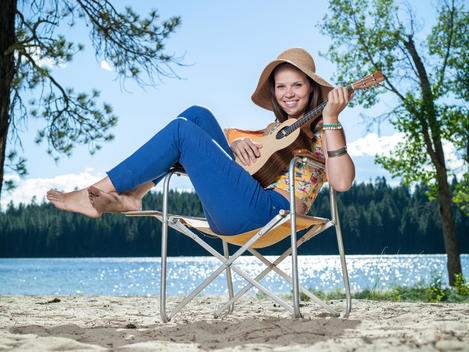 Woman on beach chair at mountain lake with ukulele