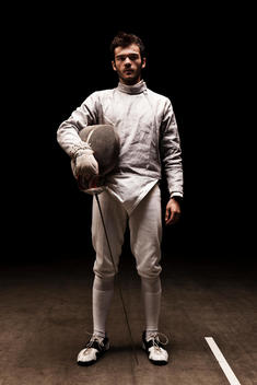 Full Body Portrait Of Fencer With Mask Off Looking At Camera.