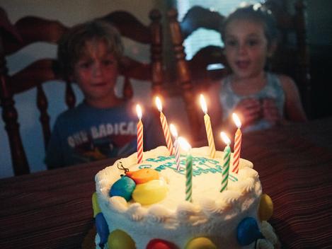 Brother and sister looking at birthday cake with candles