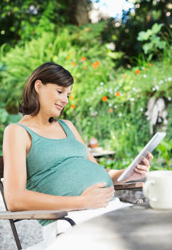 Pregnant woman using tablet computer outdoors