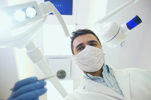 Portrait of dentist in surgical mask performing checkup