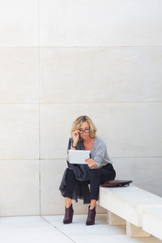 Businesswoman Sitting Outside Building Using Digital Tablet