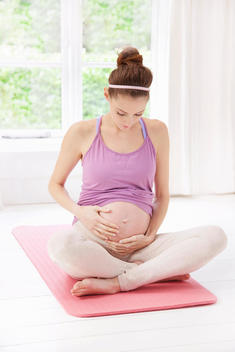 Pregnant Woman on Yoga mat Holding her Stomach