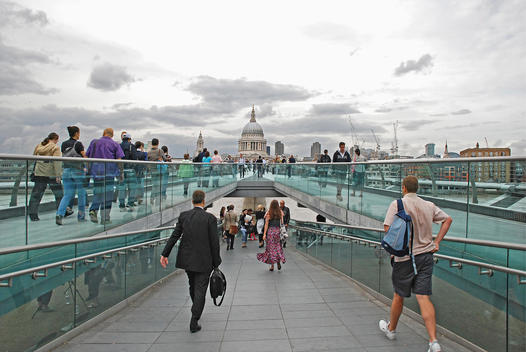 People crossing the Millennium Bridge over the River Thames connecting St. Paul\'s Cathedral on the north bank to Bankside on the south bank.