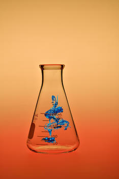 Blue Chemical Floating In Glass Container And Orange Background
