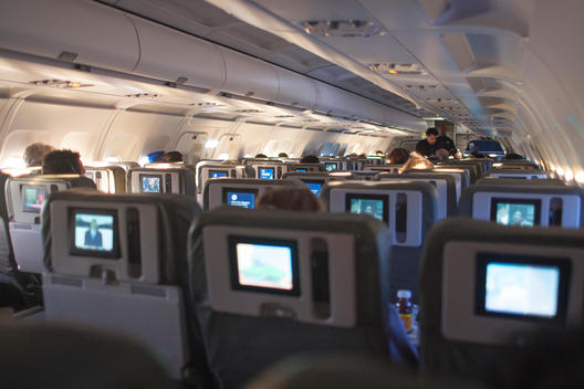 interior of airplane cabin with TV screens in the headrests