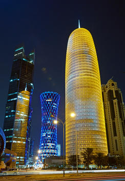 The Doha Tower (Burj Doha) and space age modern architecture along the Al Corniche street in Doha Diplomatic district illuminated at night