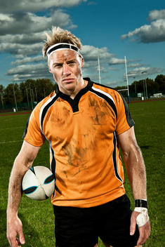 Rugby Player Holding Ball On Pitch, Portrait