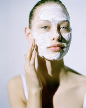 Beauty Model Applying Cream Mask To Face