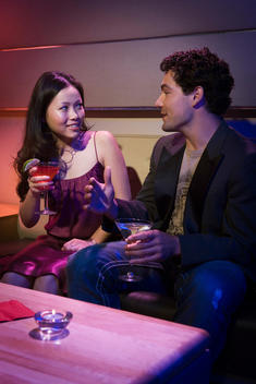 young man and woman talk over drinks at a night club