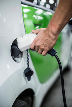 Cropped image of man charging electric car at gas station