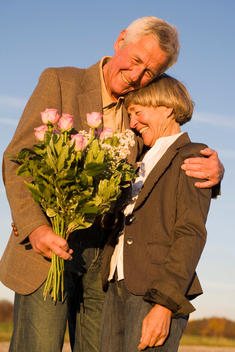 Senior couple embracing, man holding bouquet