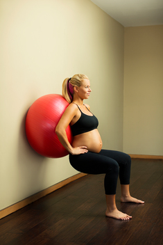 A pregnant woman works outs with a Bose ball after a yoga class in a yoga studio.