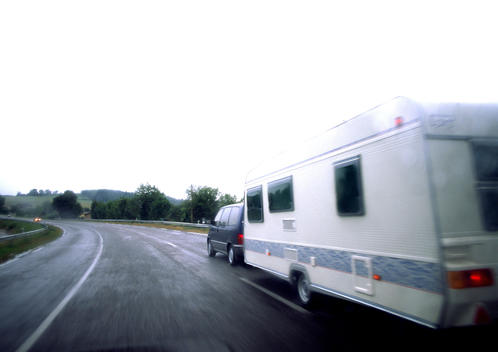 Car with mobile home driving on road, blurry.