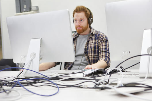 Young web designers on computer using headphones