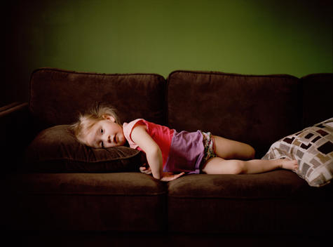 A young girl plays on the couch in the living room of her family\'s suburban home. Denver, Colorado.