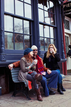 friends socializing on a bench while drinking coffee