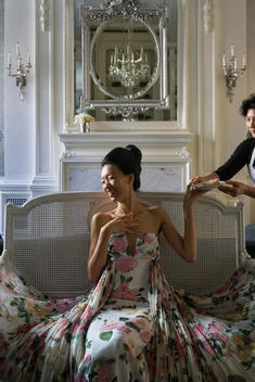 fashion model Ling Tan laughing while being served a desert plate, seated in fashion designer Zang Toi's upper east side apartment