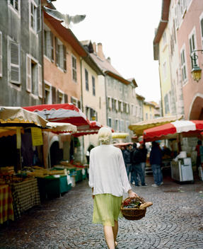 A woman walking with her shopping basket through the farmers market stands in Annecy, France.