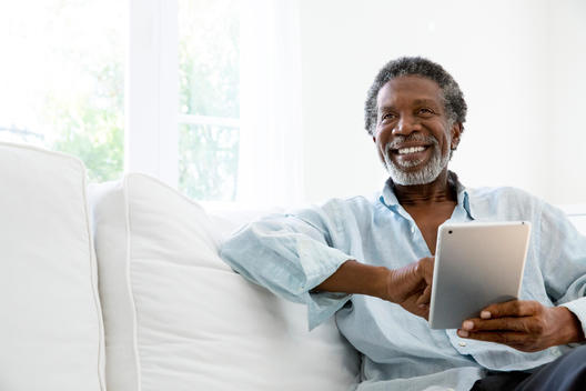 Senior man using digital tablet on sofa