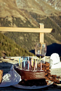 Chocolate cake with candles and wine, green landscape in background