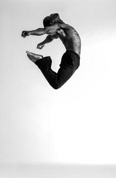 B&W image of Black male dancer jumping against white background