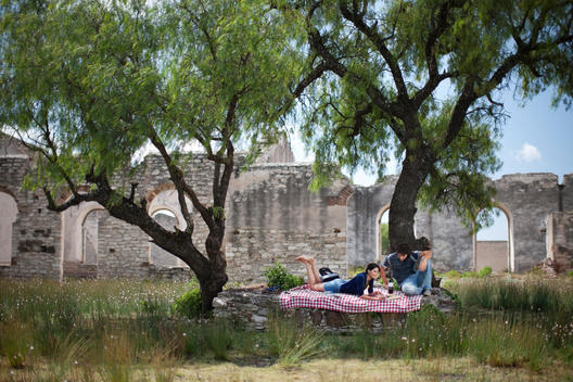 Young Couple Having A Picnic Under A Tree In The Middle Of Ruins