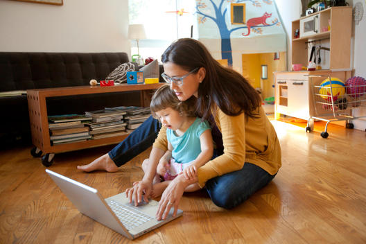 Mother and daughter sitting in front of laptop