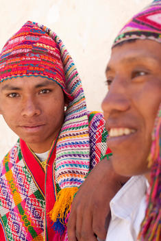 Portrait Of Two Men With Colorful Hats And Local Clothes Against White Wall