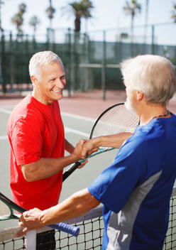 Older men shaking hands on tennis court