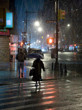 Old lady with umbrella in heavy rain at night Greenwich Village, New York City, USA.